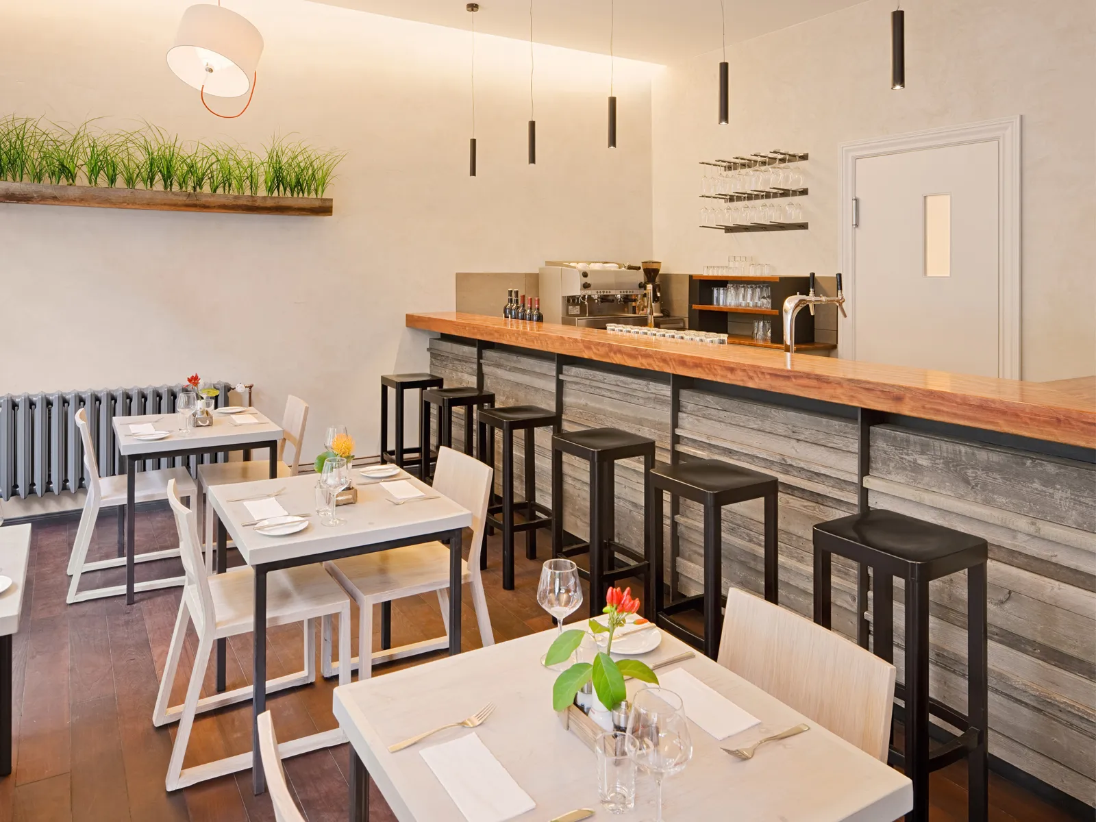 Weitwinkelaufnahme eines kompletten Bar-Bereichs inklusive Kaffeestation und Barhockern.